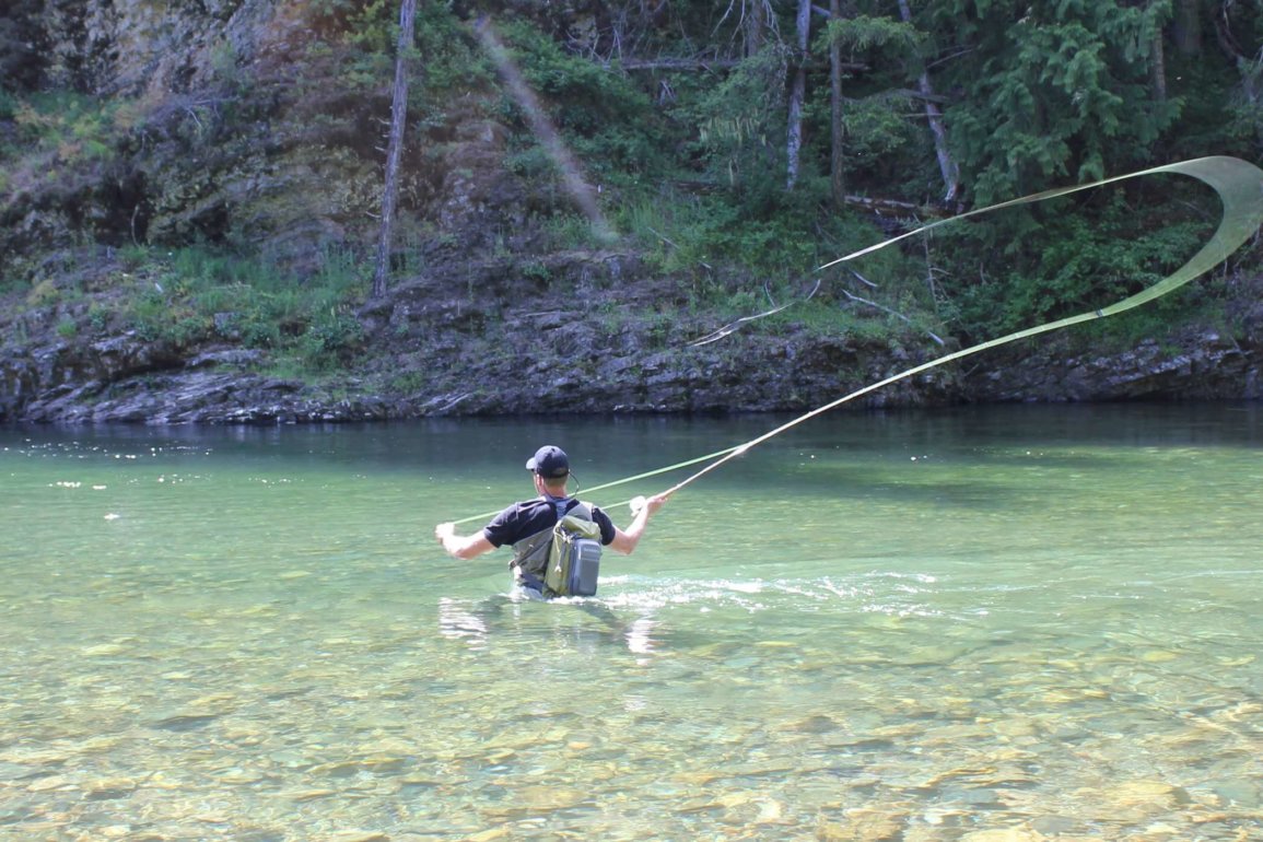 The author wades in a river while testing wading boots and fly fishing.
