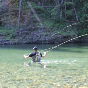 This best wading boot photo shows a person wading in a river while wearing wading boots and waders while fly fishing.