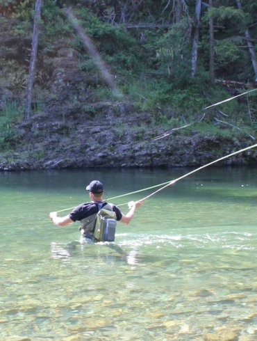 The author wades in a river while testing wading boots and fly fishing.