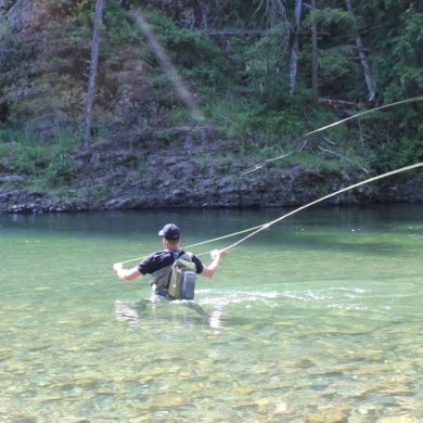 The author wades in a river while testing wading boots and fly fishing.