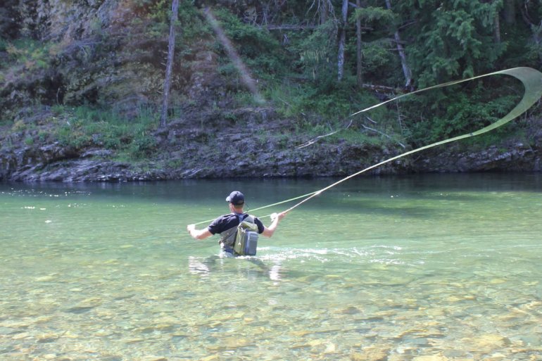 This best wading boot photo shows a person wading in a river while wearing wading boots and waders while fly fishing.