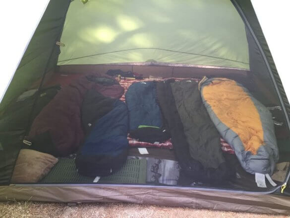 a pitched slumberjack daybreak 6 tent with sleeping bags inside of it