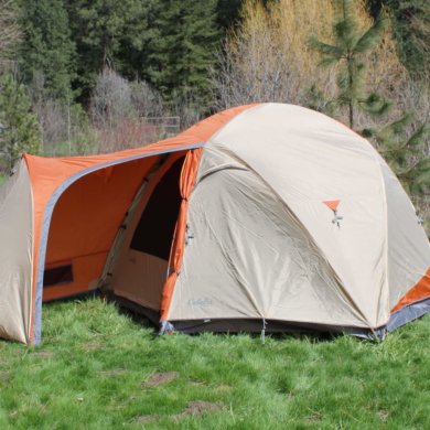 This image shows the Cabela's West Wind Dome Tent in the 6-person version outside at a camping site.
