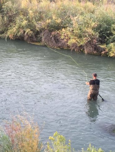 This image shows the Frogg Toggs Hellbenders fishing waders in action fly fishing on a river.