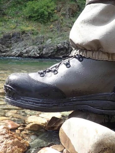 This image shows the Simms Freestone wading boot at the river's edge.