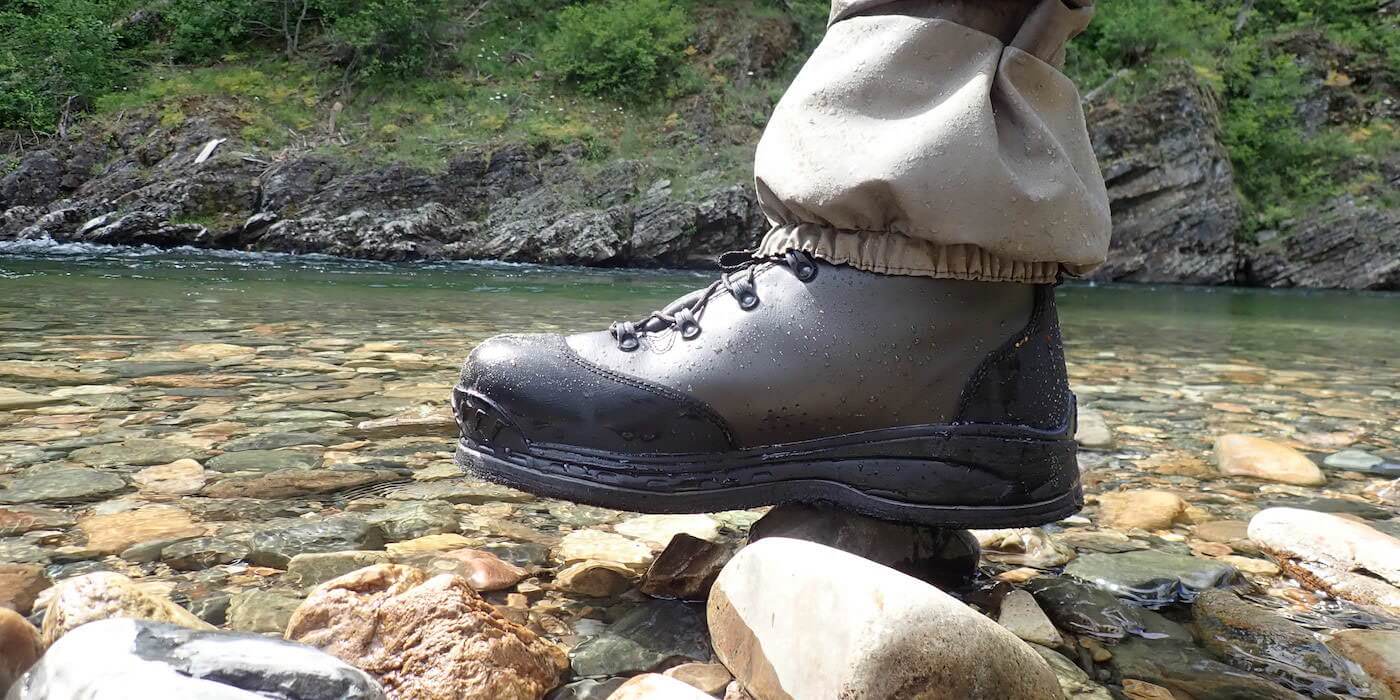 This image shows the Simms Freestone wading boot at the river's edge.
