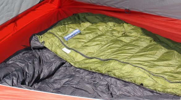 This image shows the Feathered Friends Flicker down quilt sleeping bag inside of a backpacking tent.