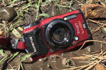 This image shows the Olympus Tough TG-5 waterproof camera in the mud on the ground.