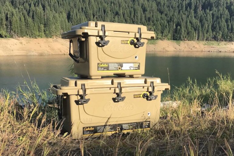 This image shows the Cabela’s Polar Cap Equalizer Cooler on the bank of a lake.