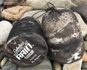 This hunting gift image shows the Cabela's Space Rain Jacket and Pants in their stuff sacks.