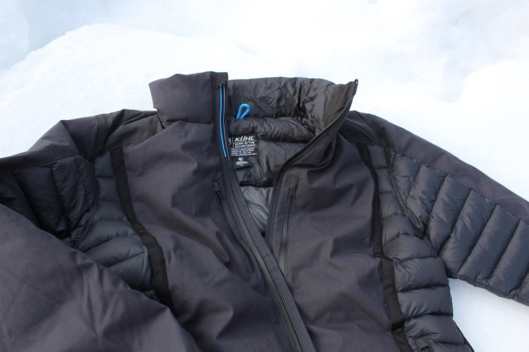 This image shows the KÜHL Firestorm Down Jacket on snow.