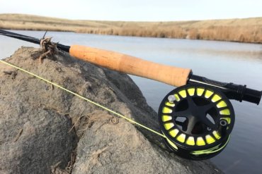 This photo shows the Cabela's Rogue Fly Rod on a rock near a creek.
