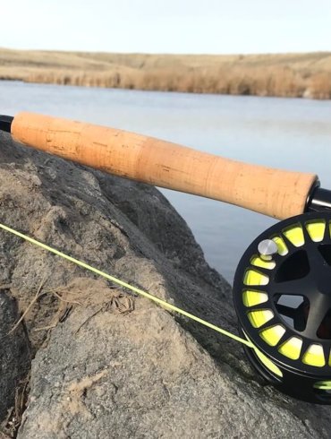 This photo shows the Cabela's Rogue Fly Rod on a rock near a creek.