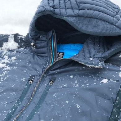 This photo shows a closeup of the KUHL SPYFIRE HOODY down jacket with a small bit of snow.