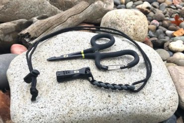 This photo shows the Loon Outdoors Rogue Quick Draw Forceps with the Nip n Sip 2.0 nippers on a river rock.