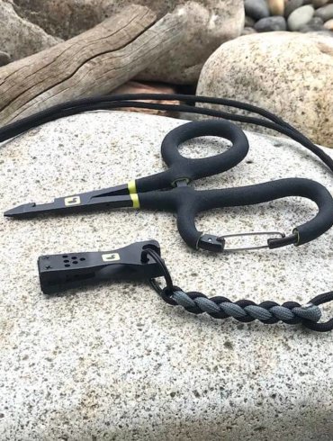 This photo shows the Loon Outdoors Rogue Quick Draw Forceps with the Nip n Sip 2.0 nippers on a river rock.