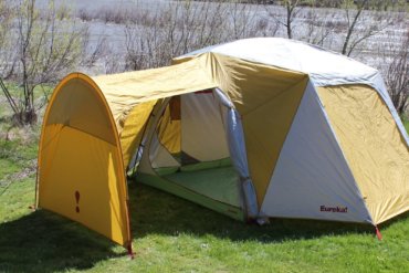 This photo shows the Eureka! Boondocker Hotel 6 Tent set up next to a river at a camping site.
