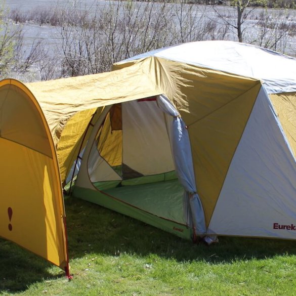 This photo shows the Eureka! Boondocker Hotel 6 Tent set up next to a river at a camping site.