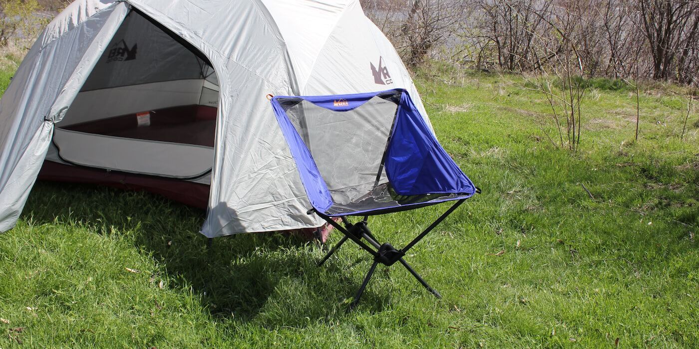 This camp chair photo shows the REI Co-op Flexlite Macro Chair in front of a tent.