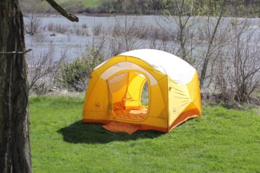 This photo shows the Big Agnes Big House 4 Deluxe camping tent set up near a river.