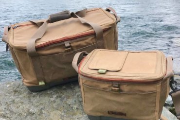 This photo shows the Fishpond Ice Storm and Blizzard Soft Coolers on a rock near a river.
