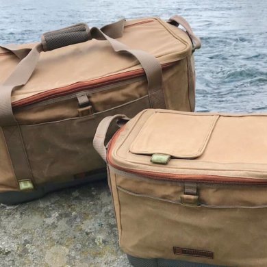 This photo shows the Fishpond Ice Storm and Blizzard Soft Coolers on a rock near a river.