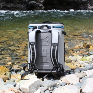 This photo shows the YETI Hopper BackFlip 24 backpack cooler on the side of a river.