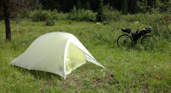 This photo shows the Big Agnes Fly Creek HV2 Platinum Tent set up in the forest next to a bikepacking bike.