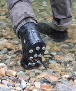 This photo shows the Korkers Triple Threat Aluminum Hex Disc Soles being worn on wading boots in a river.