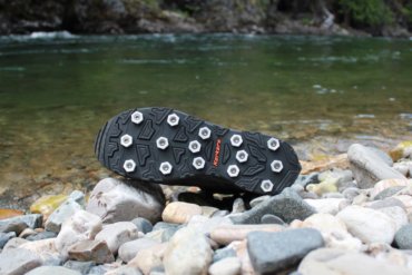 This photo shows the Korkers Triple Threat Aluminum Hex Disc Soles next to a river.