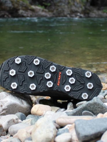This photo shows the Korkers Triple Threat Aluminum Hex Disc Soles next to a river.