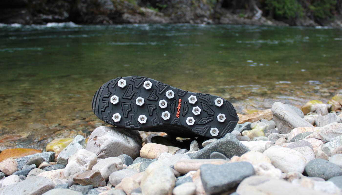 This photo shows the Korkers Triple Threat Aluminum Hex Disc Soles next to a river.
