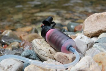 This photo shows the MSR TrailShot water filter near a river.