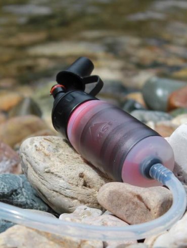This photo shows the MSR TrailShot water filter near a river.