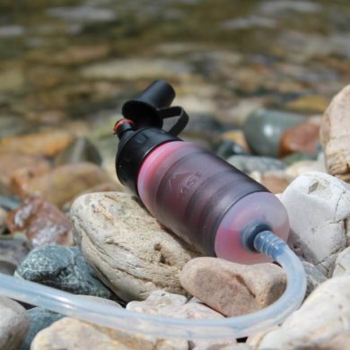 This photo shows the MSR TrailShot water filter near a river.