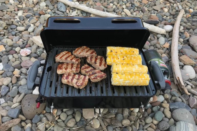 This photo shows the Weber Go-Anywhere Gas Grill with steak and corn on the cob grilling.
