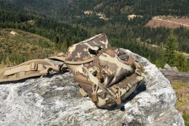 This photo shows the Alaska Guide Creations Classic MAX Pack Bino Harness on a rock outside by a forest.