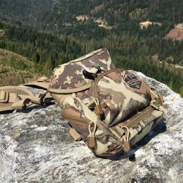 This photo shows the Alaska Guide Creations Classic MAX Pack Bino Harness on a rock outside by a forest.