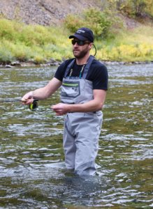 This photo shows a fly fisher wearing the Orvis Ultralight Convertible Waders while fishing on a river.