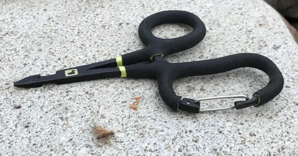 This photo shows the Loon Outdoors Rogue Quickdraw Forceps on a rock outside. 
