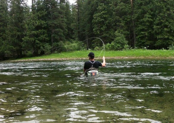 This photo shows a fly fisherman wading with a Fishpond Thunderhead Submersible Lumbar Pack that is slightly submerged.