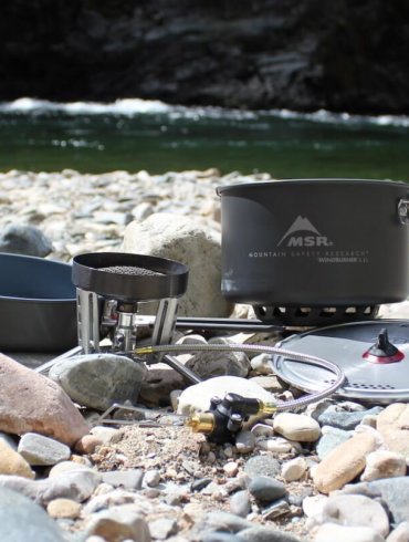 This photo shows the MSR WindBurner Stove System Combo outside near a mountain river.