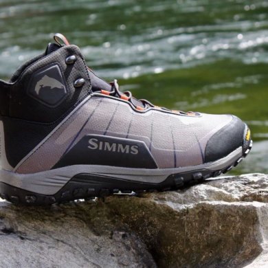 This Simms Flyweight Wading Boot Review photo shows a Simms Flyweight Wading Boot on a rock with a river in the background.
