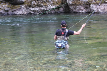 This photo shows a fly fisherman wading in a river while wearing the Umpqua Tongass 650 Waterproof Waist Pack.