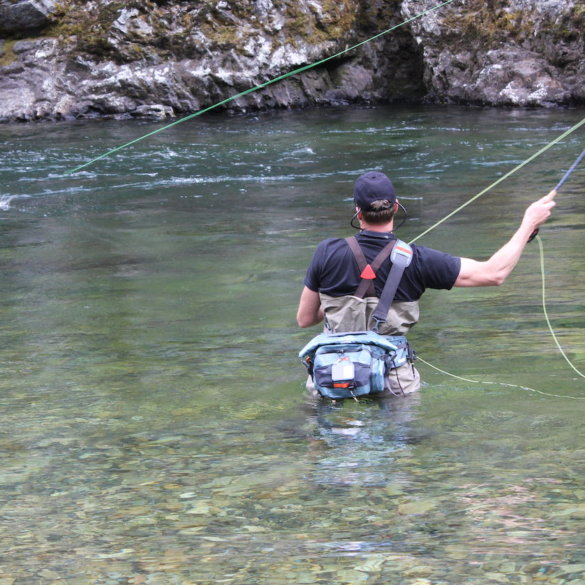 This photo shows a fly fisherman wading in a river while wearing the Umpqua Tongass 650 Waterproof Waist Pack.