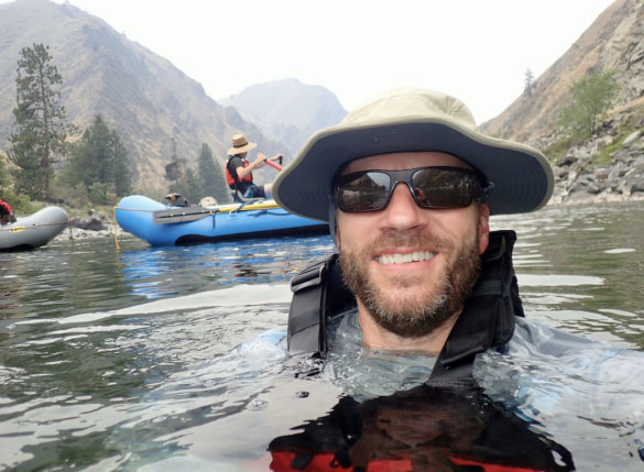 This photo shows the author testing the Shelta Firebird V2 sun hat in a river while whitewater rafting during the long-term review process.