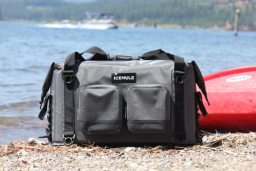 This photo shows the ICEMULE Traveler soft-sided cooler on a beach near water.