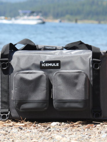This photo shows the ICEMULE Traveler soft-sided cooler on a beach near water.
