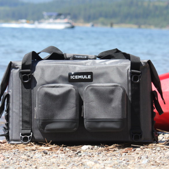 This photo shows the ICEMULE Traveler soft-sided cooler on a beach near water.