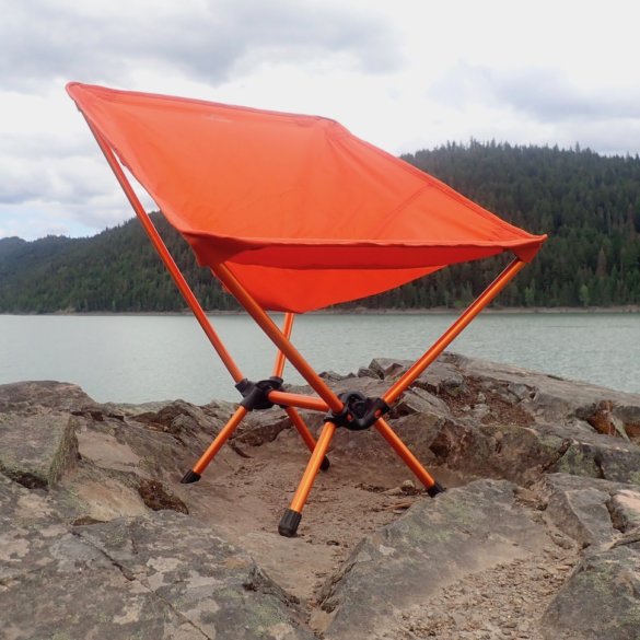 This gear review photo shows the REI Co-op Flexlite Air Chair on a rock above a lake.